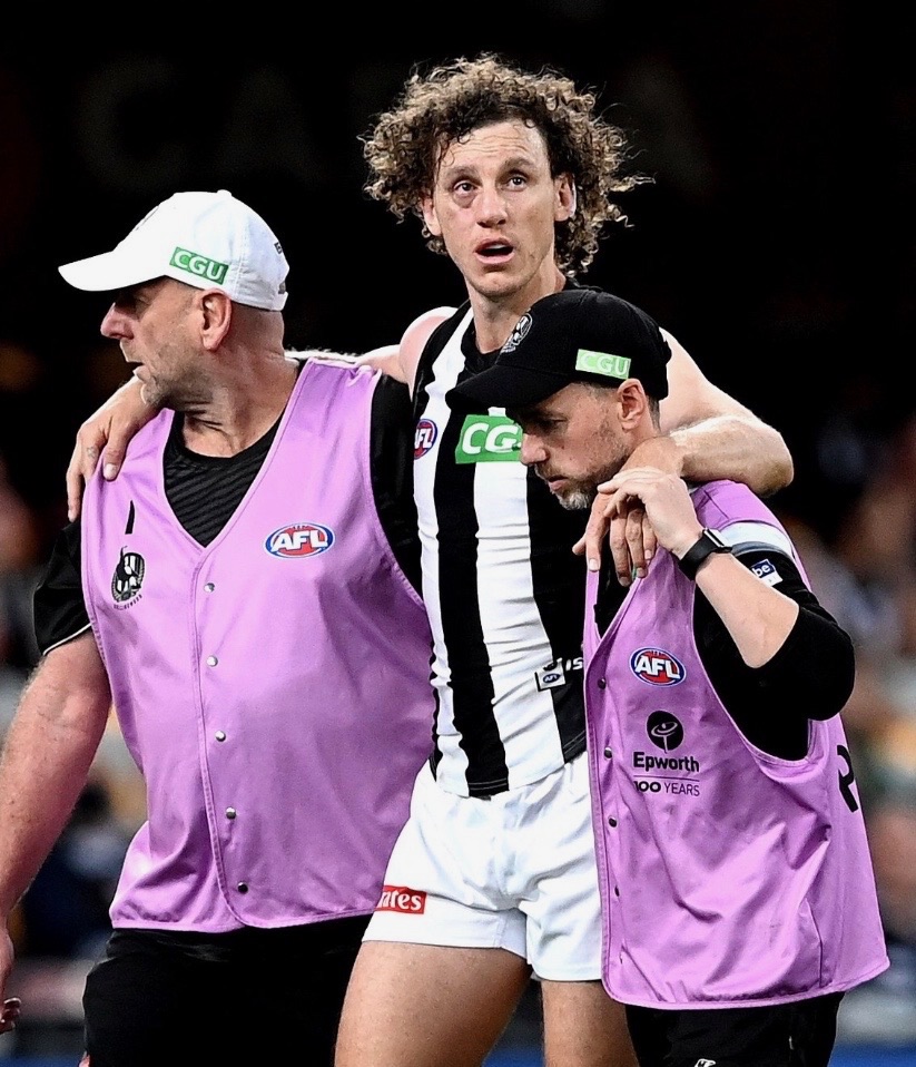 Lachlan Fooks helping an injured AFL player from the ground on match day