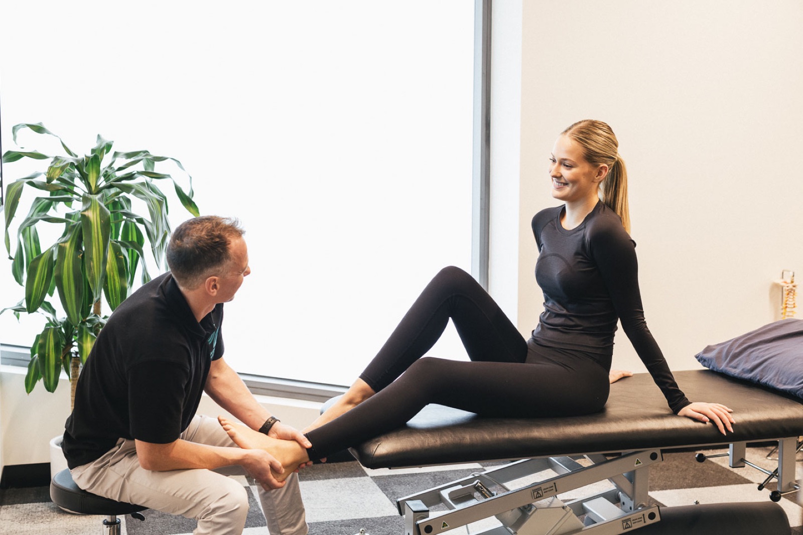 Performe physiotherapist assessing a runner's ankle and lower leg