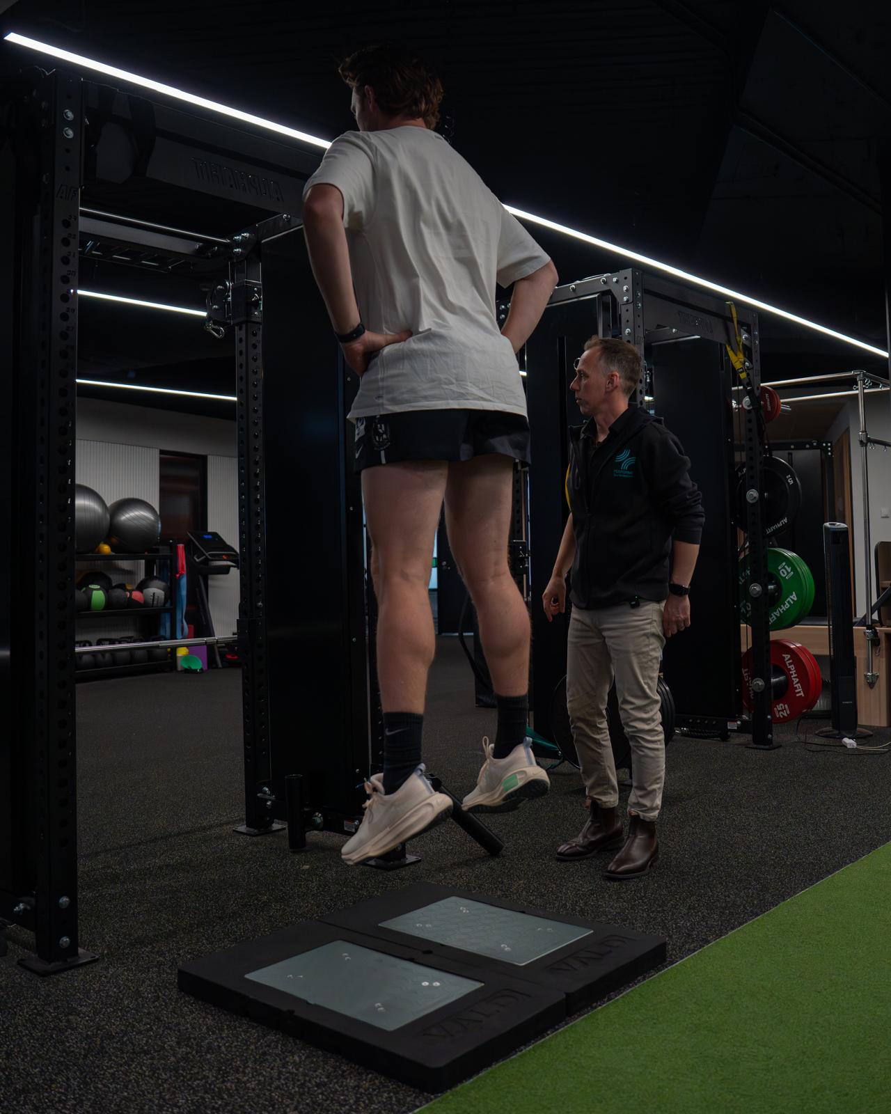 Athlete performing a jump assessment on force plates, supervised by a Performe clinician