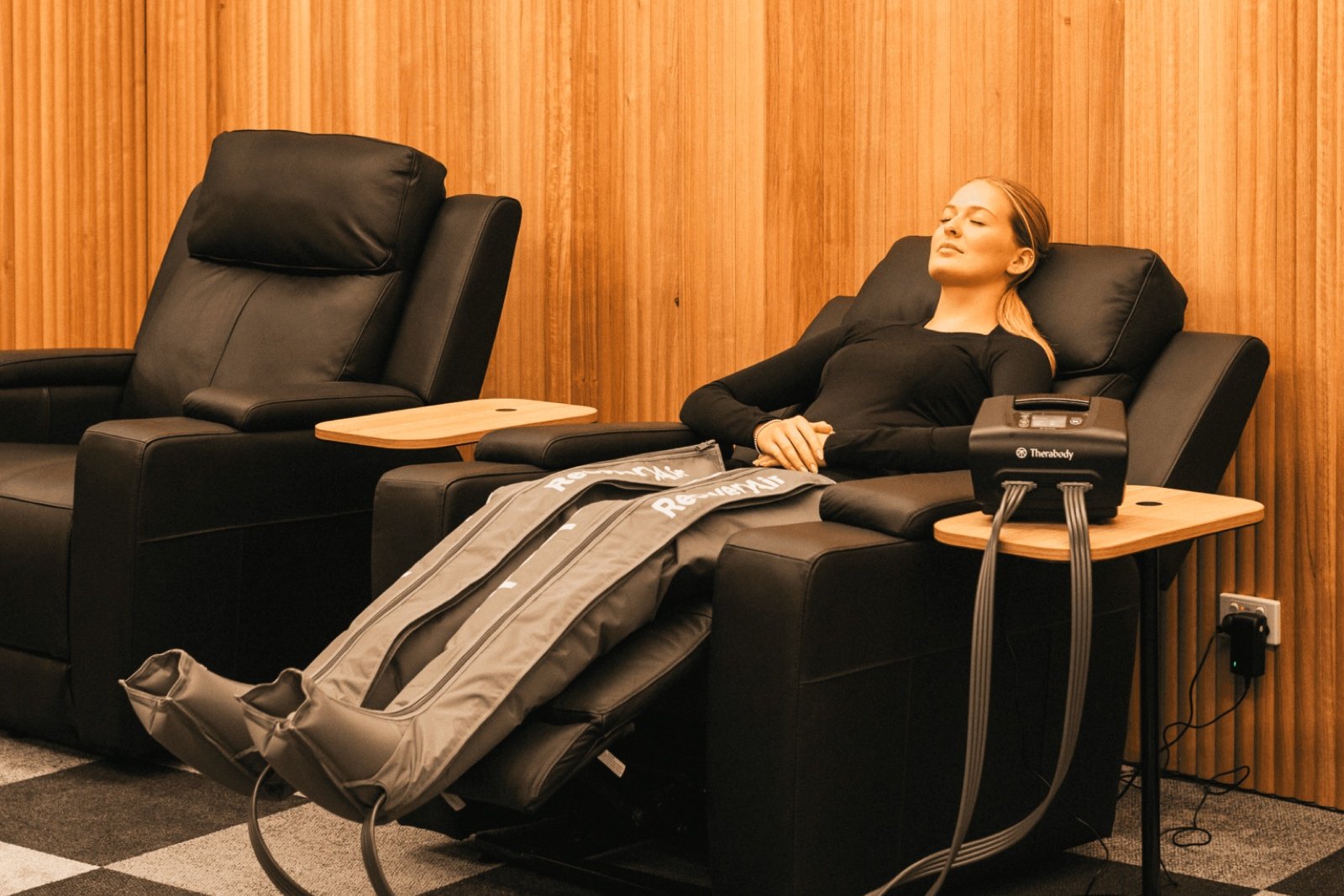 Athlete relaxing in a recovery chair wearing compression boots at Performe Sports Medicine